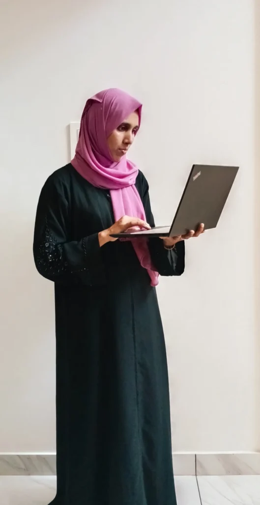 muhsina - digital marketing strategist in palakkad is standing while holding laptop.